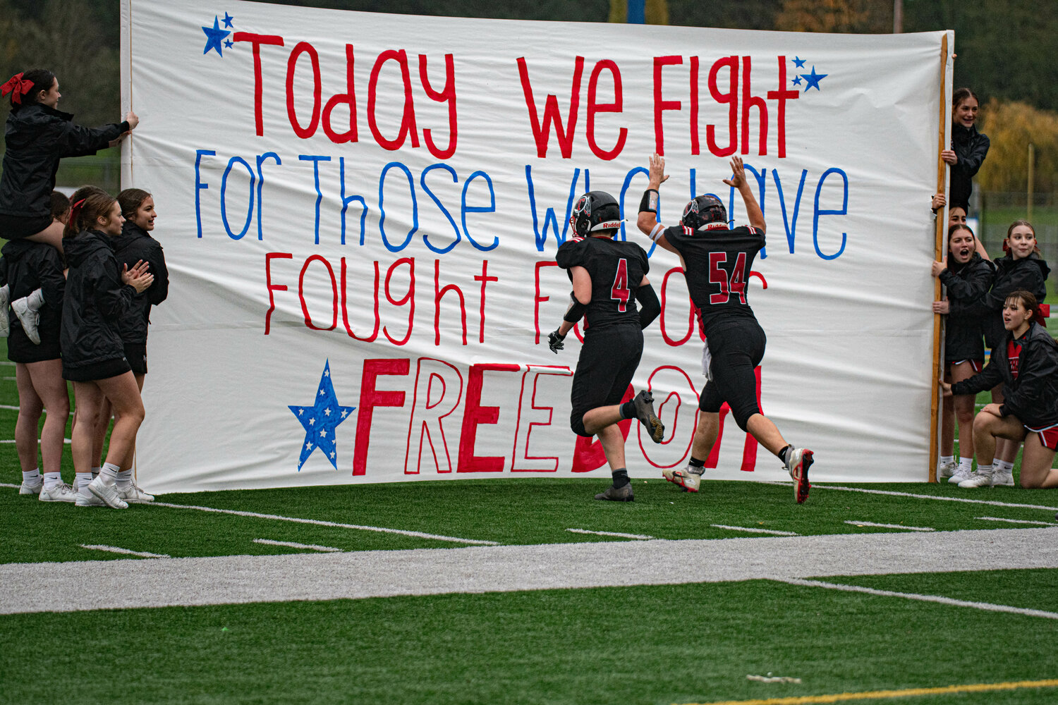 The Toledo football team takes the field by running through a veterans day themed banner  during a 21-12 win over Tri Cities Prep Nov. 11.